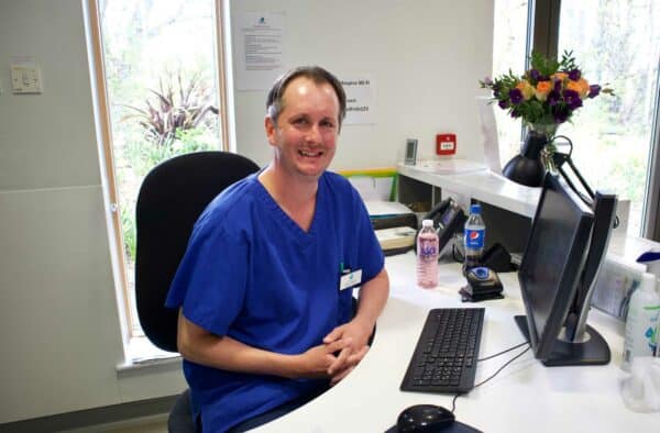 Nurse smiling at camera behind a computer on IPU