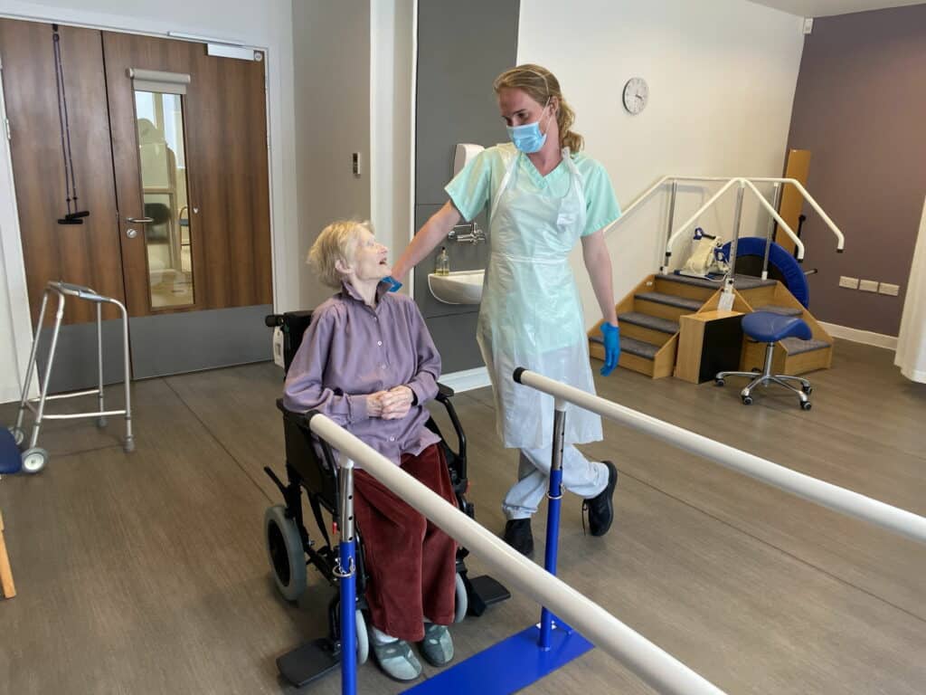 Physio standing and patient in wheel chair in gym at hospice