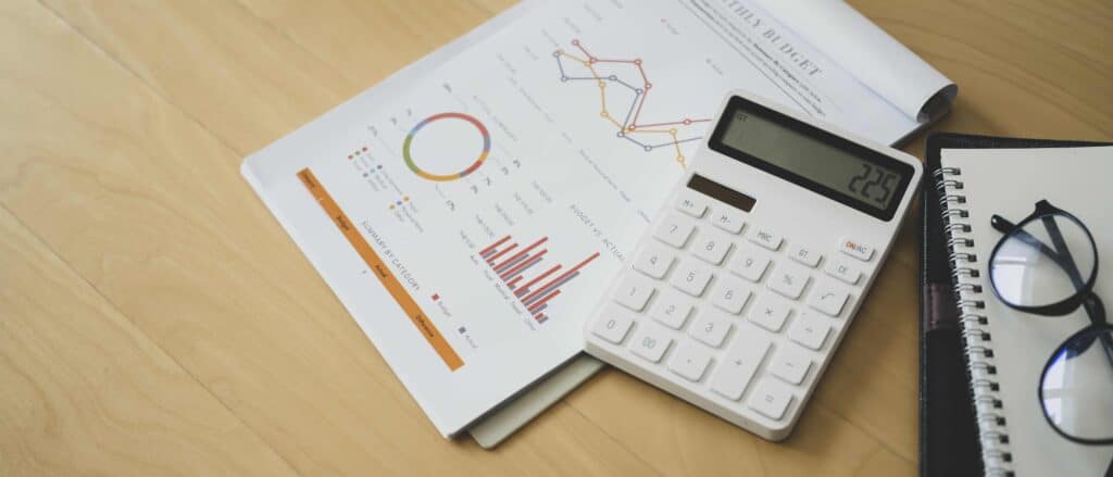 Accountant workplace with documents, calculator and notebook on wooden table.