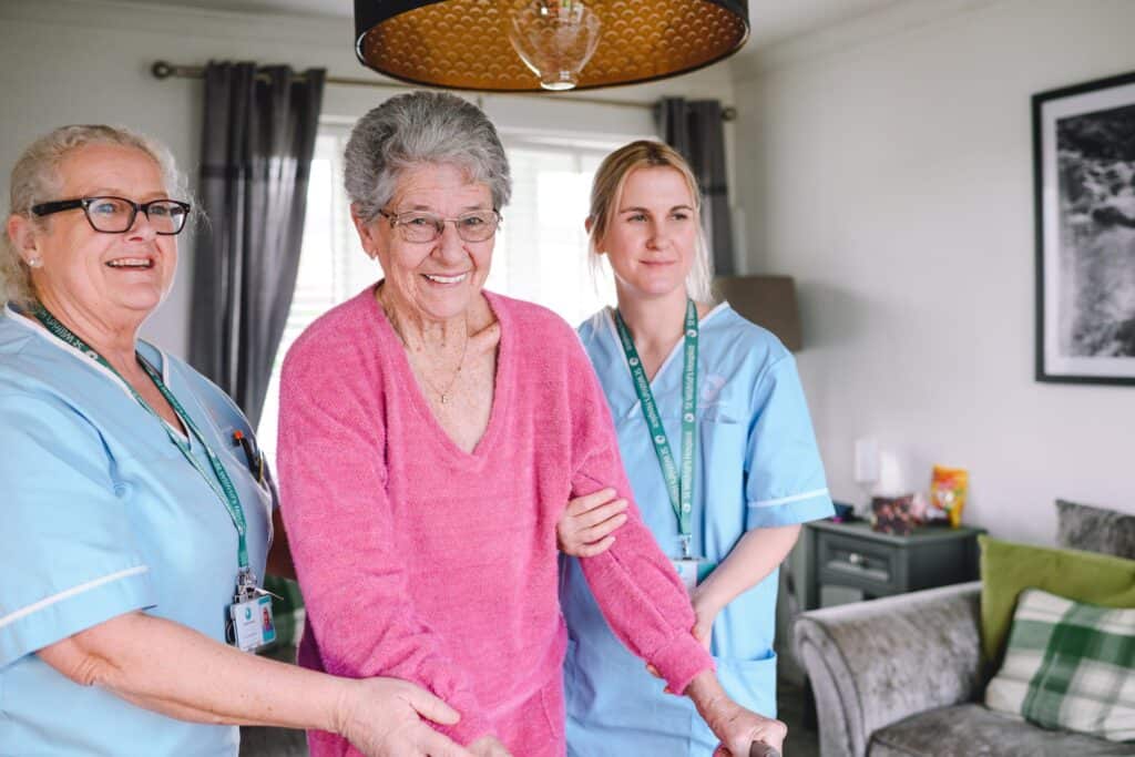 Two Healthcare Assitants help a woman to stand