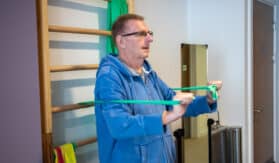 A patient uses resistance bands in the hospice's gym