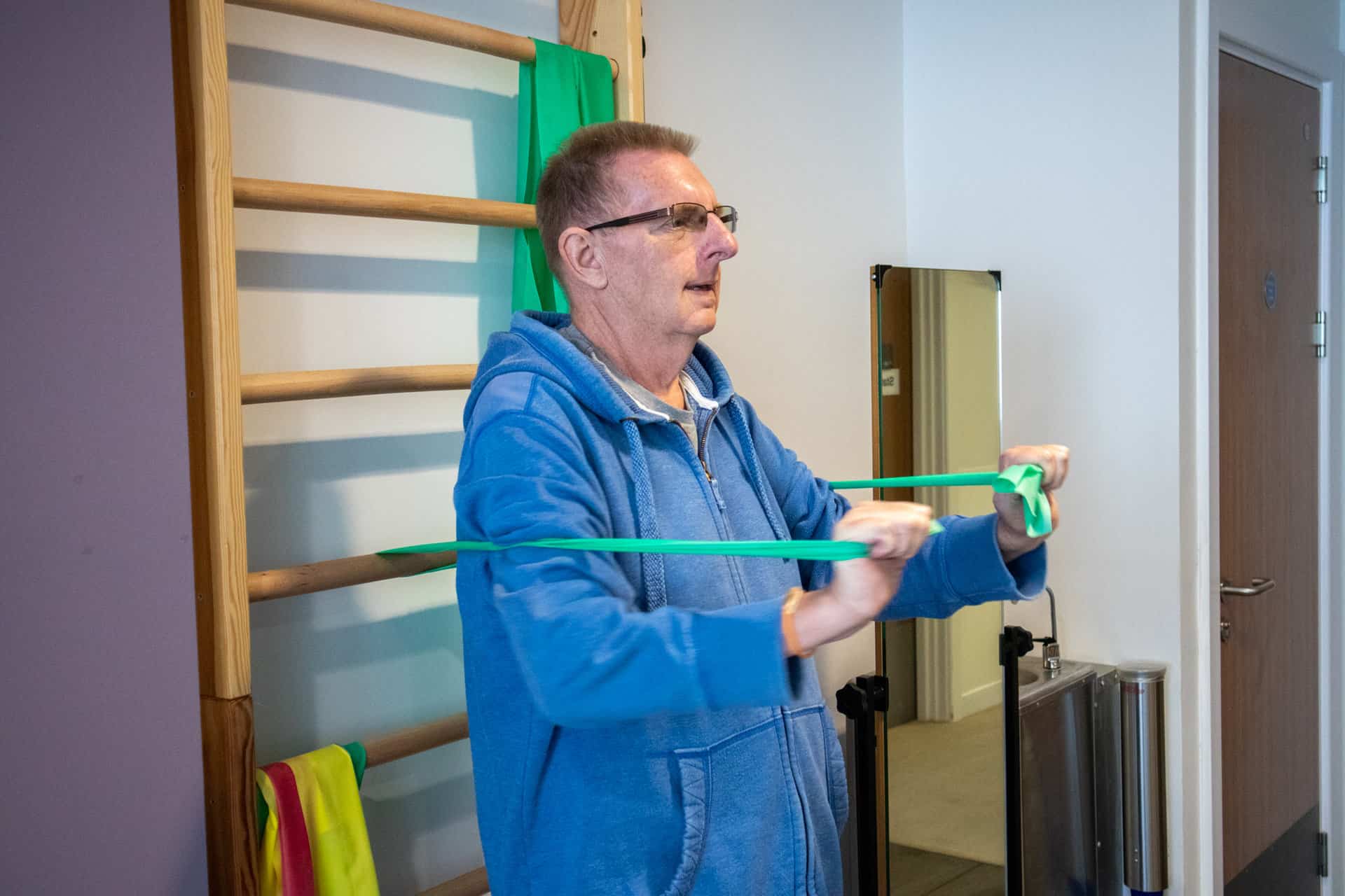 A patient uses resistance bands in the hospice's gym