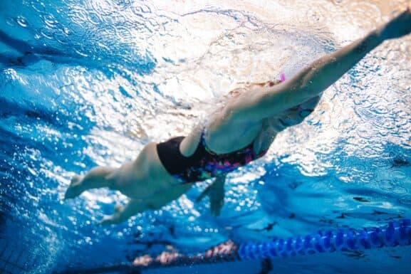 Underwater shot of professional female athlete swimming in pool. Young woman swimming the front crawl style in a pool.