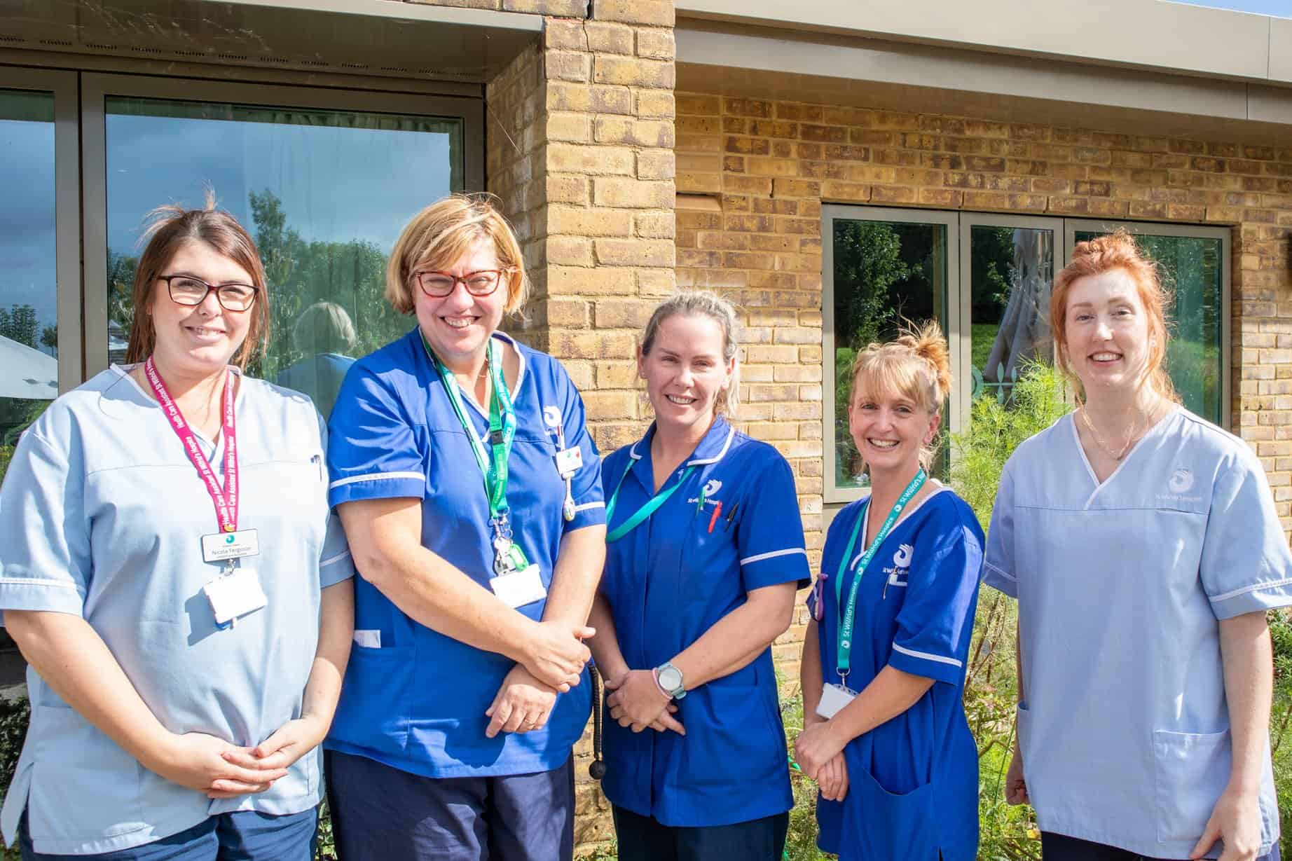 Five nurses in a line standing infront of the hospice building