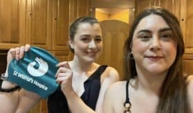 Two people in changing room holding swimming hat