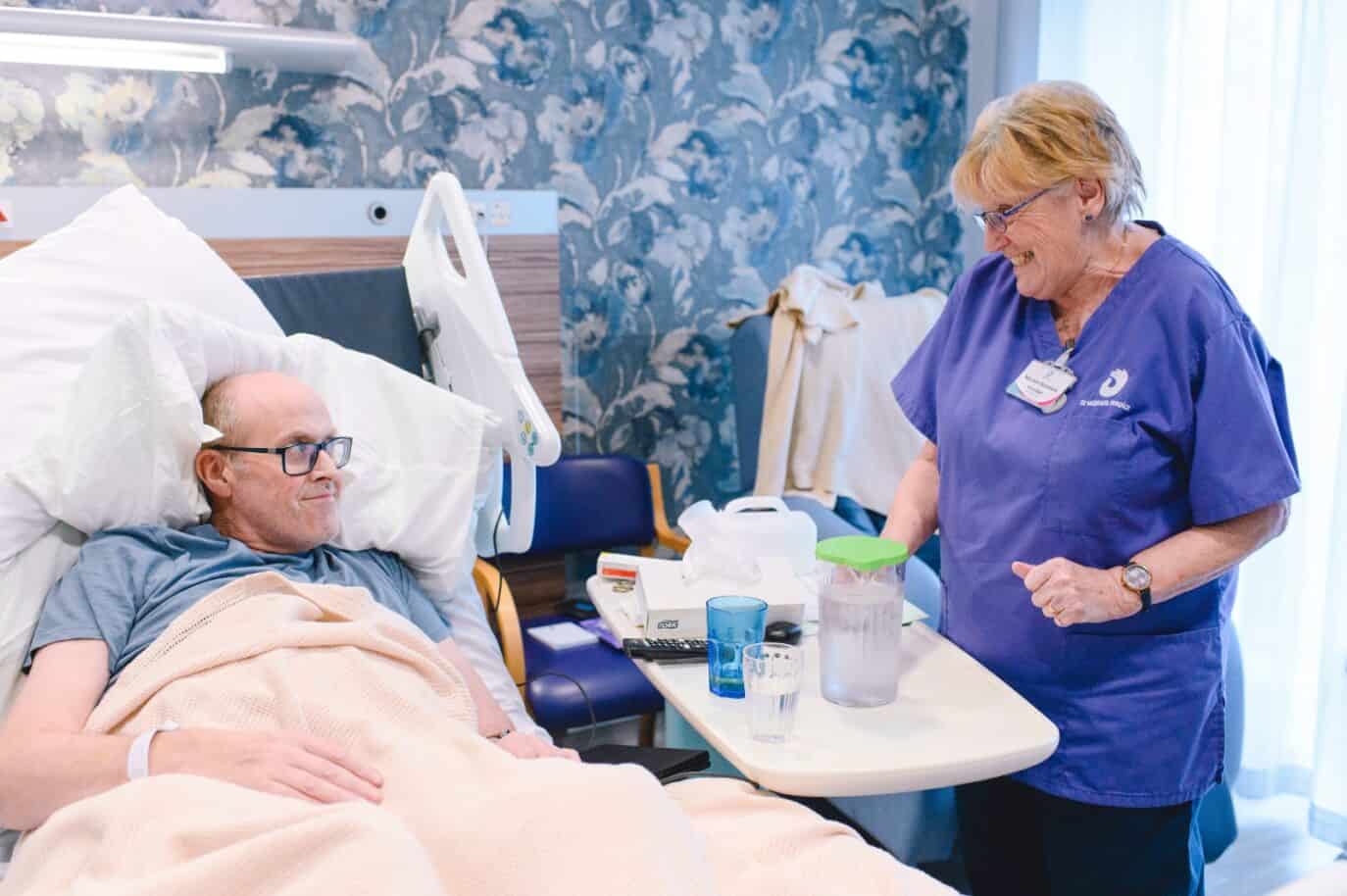 health care assistant chatting to patient in hospital bed