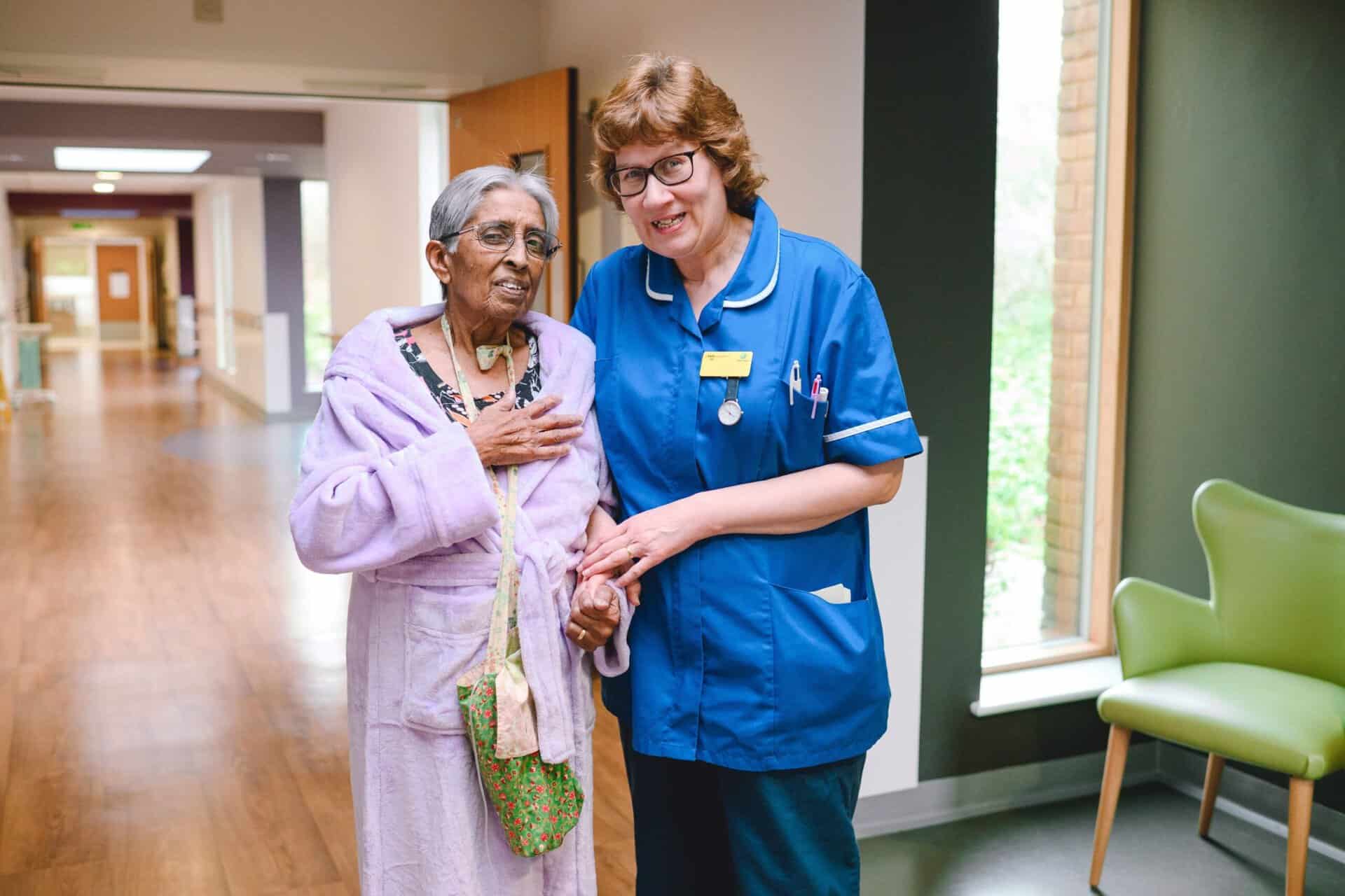 A nurse with a patient walking along a corridor