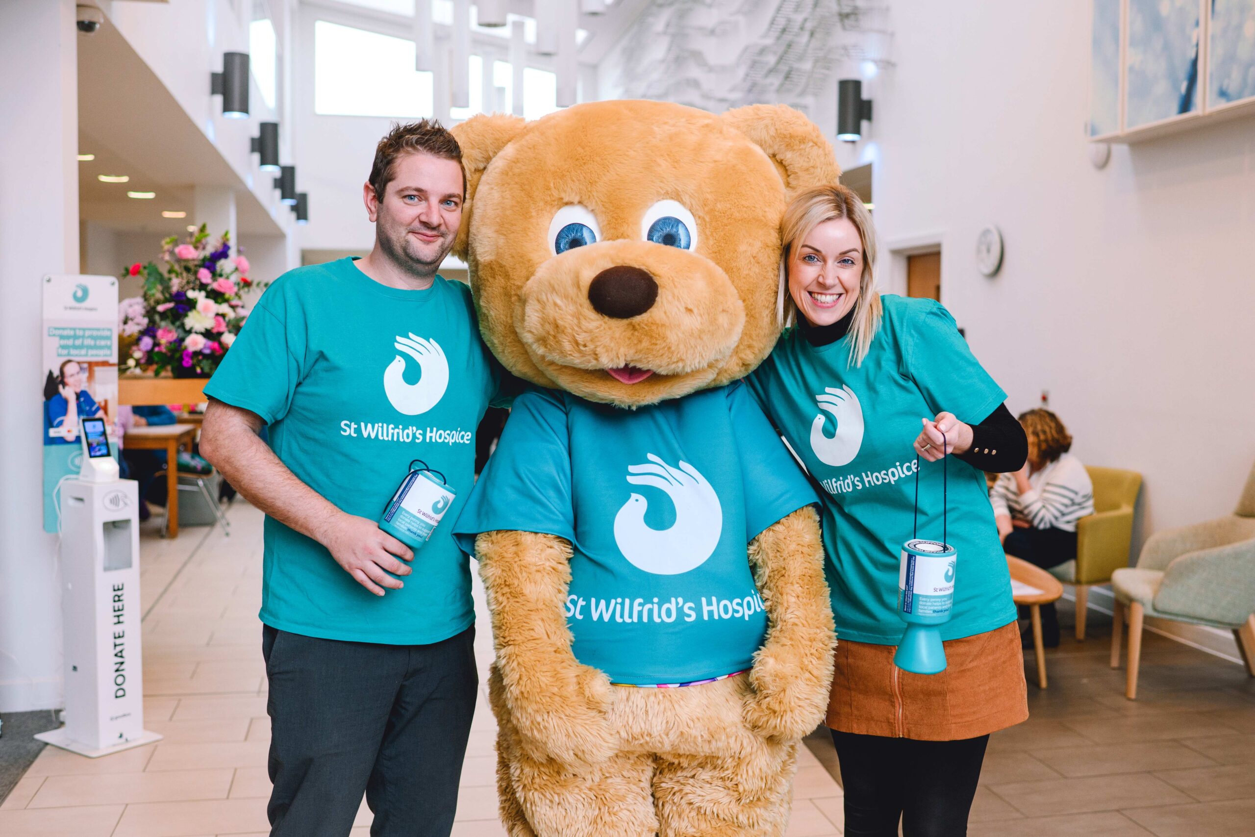 two people wearing St Wilfrid's t-shirts standing with Wilfie Bear