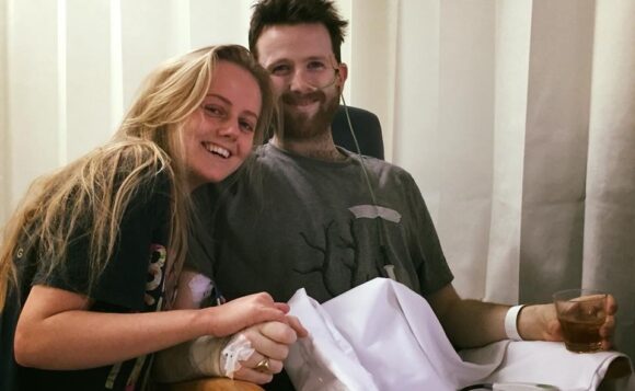patient holding hands with wife in hospice